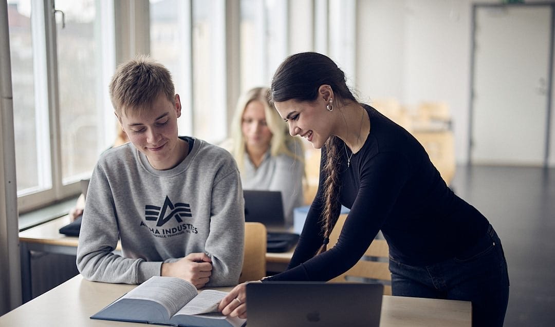 Två elever bläddrar i en bok