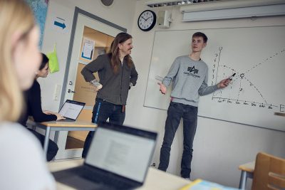Lärare och elev står framme vid tavlan i ett klassrum