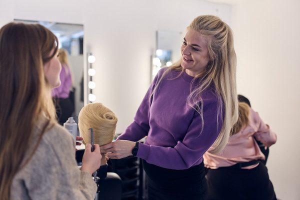 Elev sätter upp håret på en docka